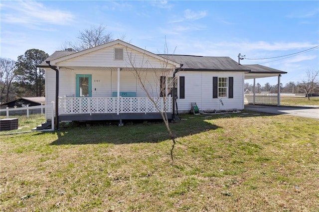 view of front facade featuring driveway, fence, covered porch, a front yard, and a carport