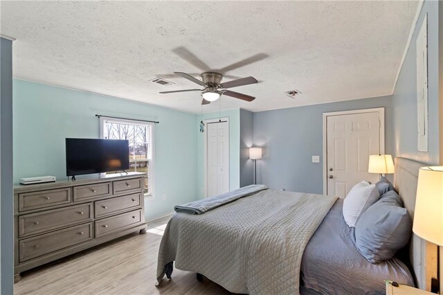 bedroom with visible vents, a ceiling fan, a textured ceiling, a closet, and light wood-style floors