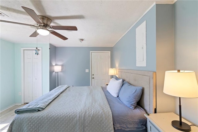 bedroom featuring wood finished floors, visible vents, ceiling fan, ornamental molding, and a textured ceiling