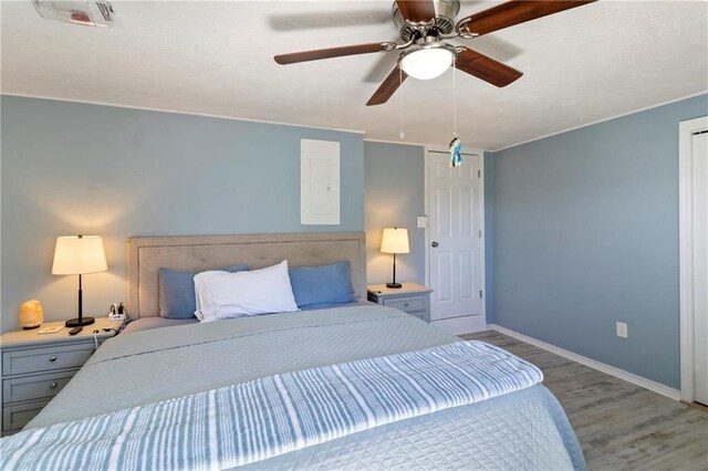 bedroom with visible vents, baseboards, electric panel, light wood-style flooring, and a ceiling fan