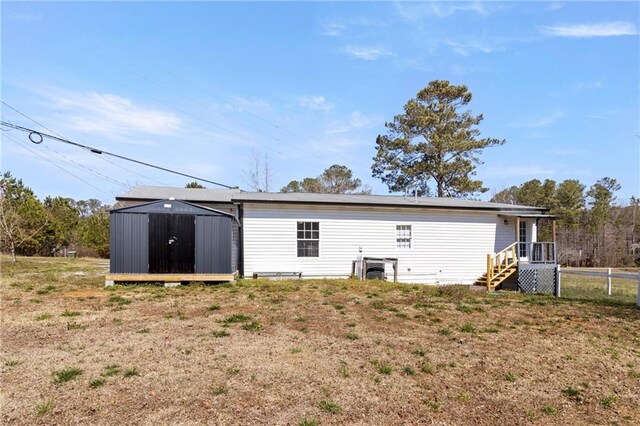 back of house with an outbuilding, a storage unit, and fence