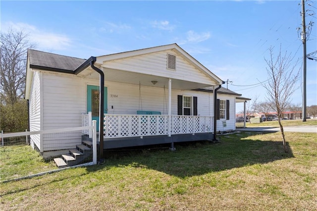 view of front facade with a front lawn, fence, and covered porch