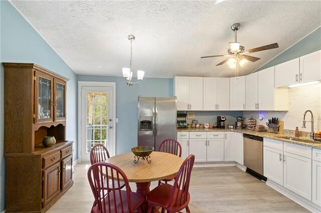 kitchen with lofted ceiling, light wood-style flooring, a sink, white cabinets, and appliances with stainless steel finishes