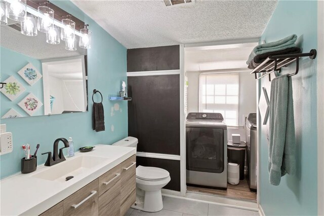 full bath featuring vanity, a textured ceiling, tile patterned floors, toilet, and independent washer and dryer