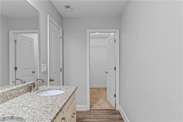 full bath with visible vents, vanity, baseboards, and wood finished floors