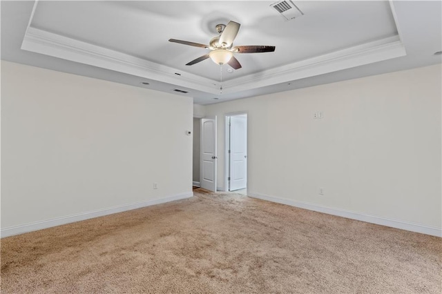 empty room with baseboards, visible vents, a raised ceiling, and light carpet