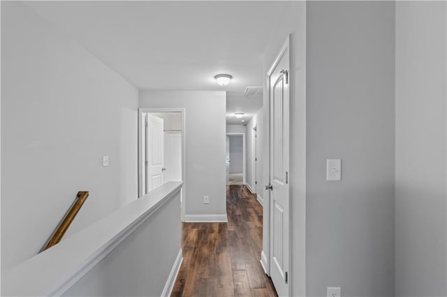 hallway with dark wood-type flooring, an upstairs landing, baseboards, and visible vents