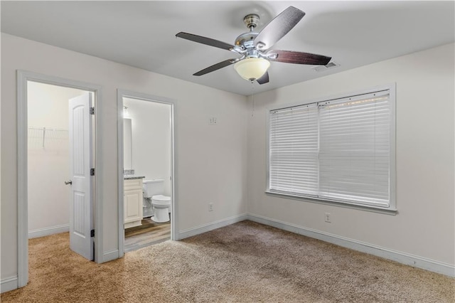 unfurnished bedroom featuring baseboards, a walk in closet, light carpet, and visible vents