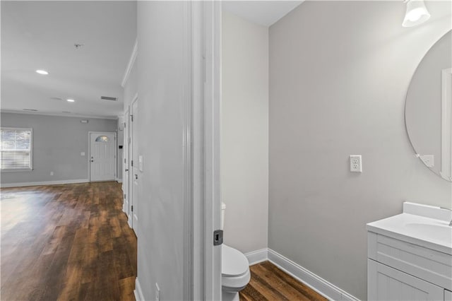 bathroom featuring baseboards, toilet, recessed lighting, wood finished floors, and vanity