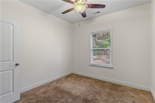 carpeted spare room with visible vents, a ceiling fan, and baseboards