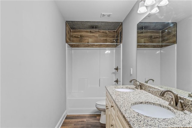 bathroom featuring double vanity, toilet, wood finished floors, and a sink