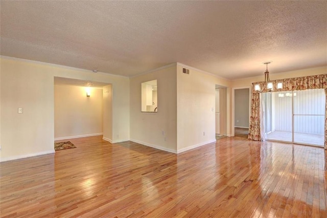 unfurnished room with a chandelier, light wood-type flooring, visible vents, and baseboards