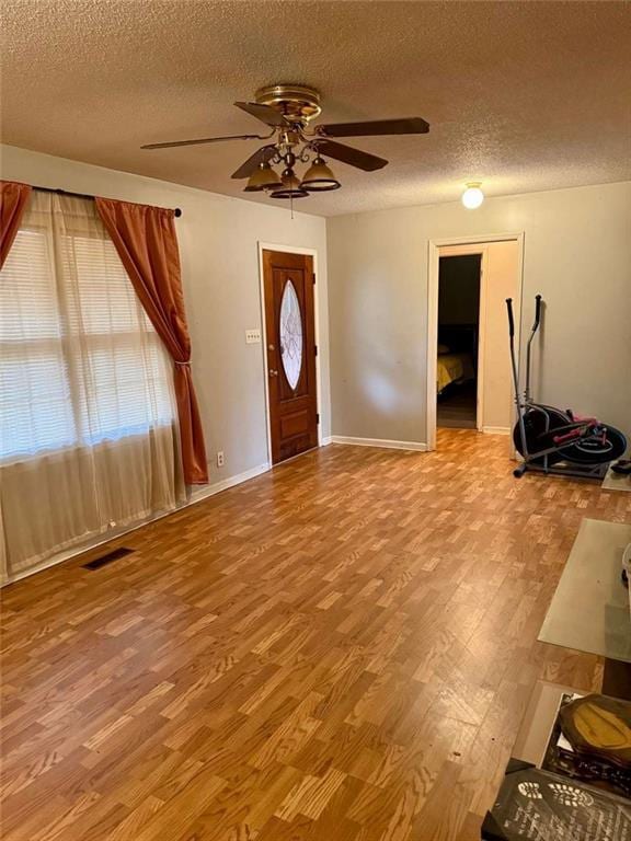 entryway with ceiling fan, light wood-type flooring, and a textured ceiling