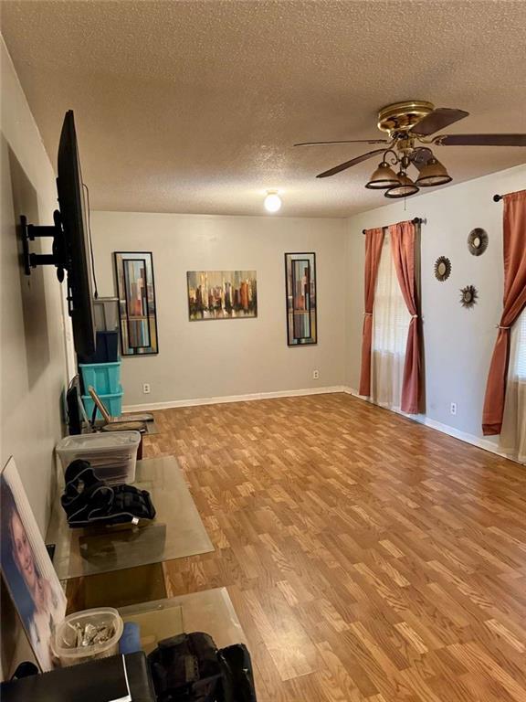 living room with ceiling fan, a textured ceiling, and light hardwood / wood-style flooring