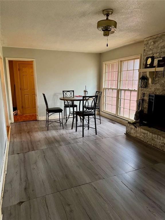 dining space featuring ceiling fan, a fireplace, and a textured ceiling