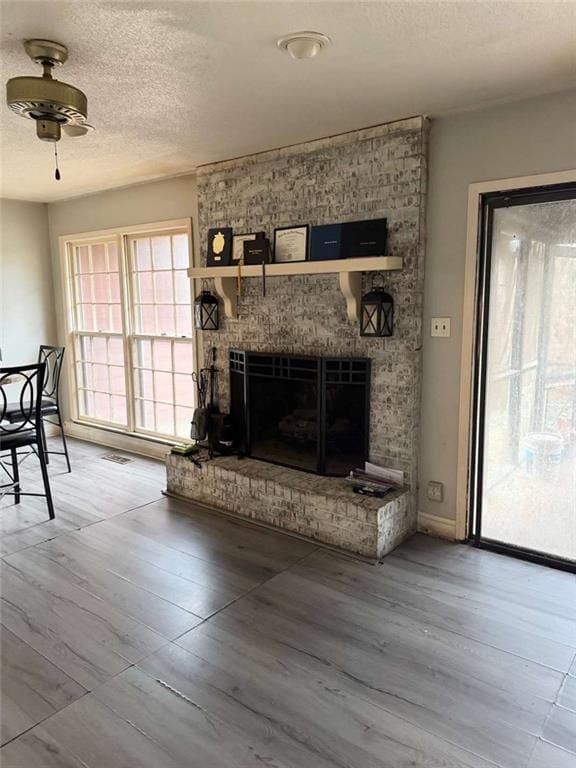 living room with ceiling fan, a wealth of natural light, a fireplace, and hardwood / wood-style flooring