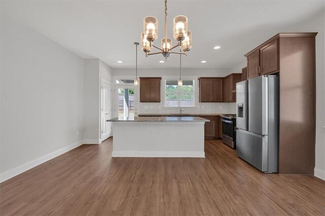 kitchen with decorative light fixtures, hardwood / wood-style flooring, appliances with stainless steel finishes, a center island, and an inviting chandelier