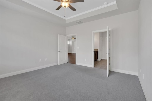 unfurnished bedroom with ceiling fan, carpet floors, a raised ceiling, and ornamental molding