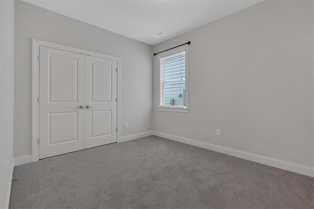 unfurnished bedroom with a closet and light colored carpet