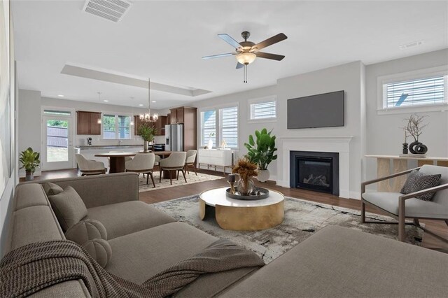 living room with light wood-type flooring and ceiling fan with notable chandelier