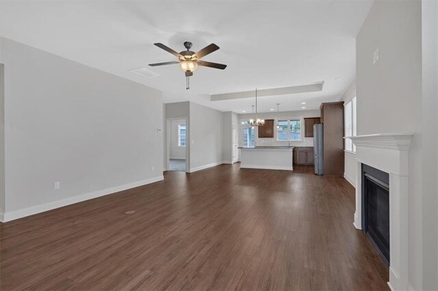 unfurnished living room featuring ceiling fan with notable chandelier and dark hardwood / wood-style floors