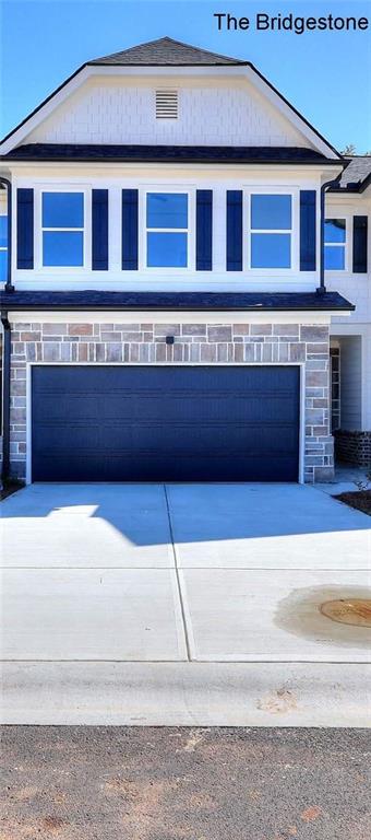 view of front of property featuring stone siding, concrete driveway, and a garage