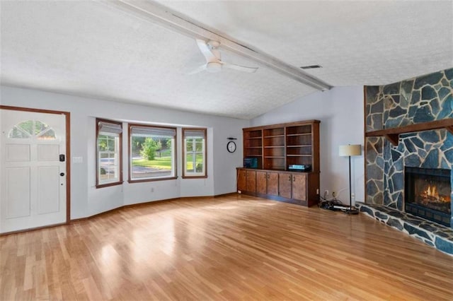 1757 Mystery Cir SW, Conyers, GA 30094 - unfurnished living room featuring wood finished floors, a textured ceiling, plenty of natural light, ceiling fan, and a stone fireplace