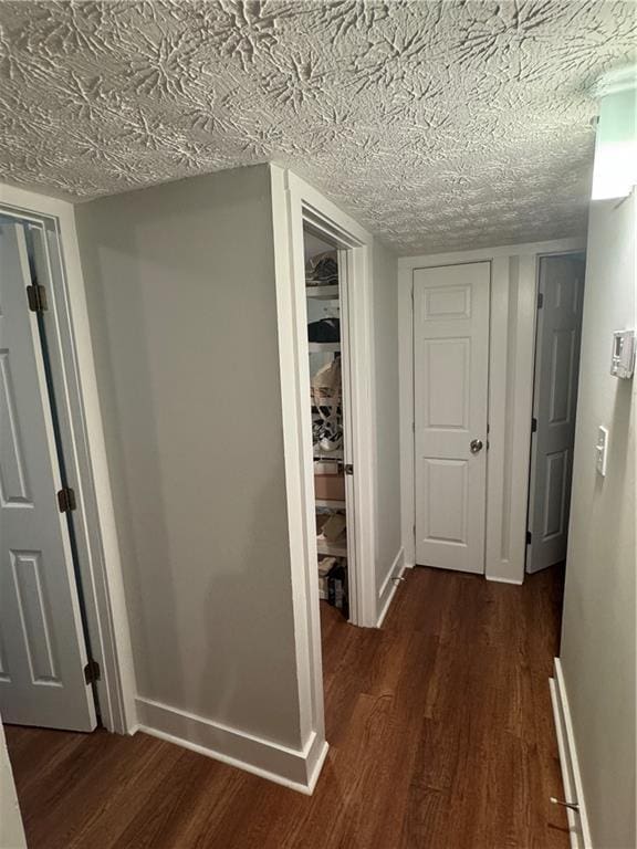 hallway featuring dark wood-type flooring and a textured ceiling