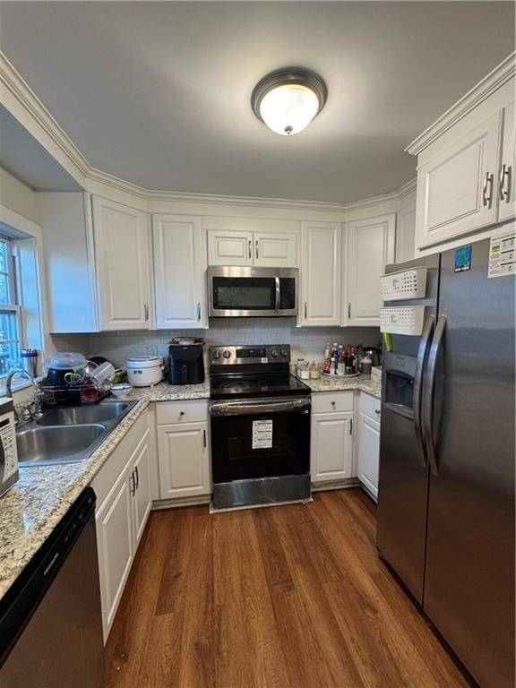 kitchen with sink, dark wood-type flooring, stainless steel appliances, backsplash, and white cabinets