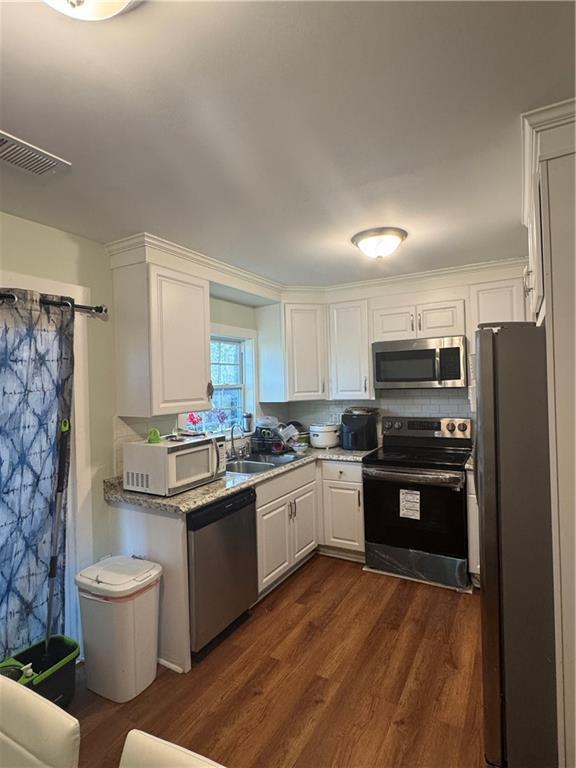 kitchen with appliances with stainless steel finishes, dark hardwood / wood-style flooring, tasteful backsplash, sink, and white cabinetry