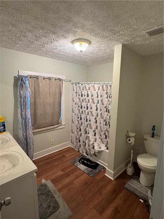 full bathroom with wood-type flooring, vanity, a textured ceiling, and toilet