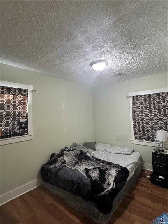 bedroom with a textured ceiling and dark wood-type flooring