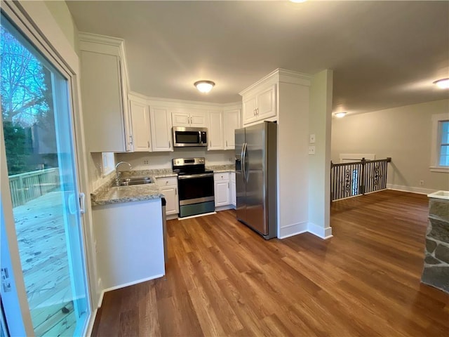 kitchen featuring sink, dark wood-type flooring, light stone counters, white cabinets, and appliances with stainless steel finishes