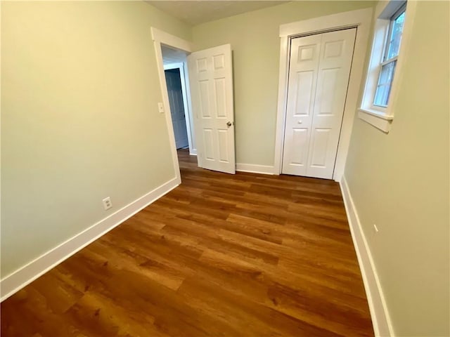 unfurnished bedroom featuring dark hardwood / wood-style flooring and a closet