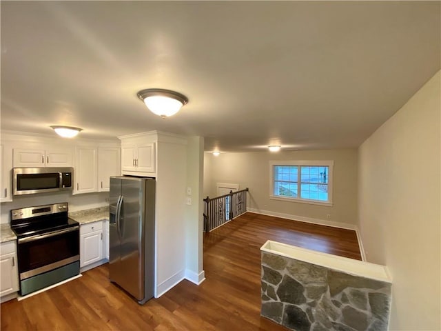 kitchen featuring dark hardwood / wood-style floors, light stone countertops, white cabinetry, and stainless steel appliances