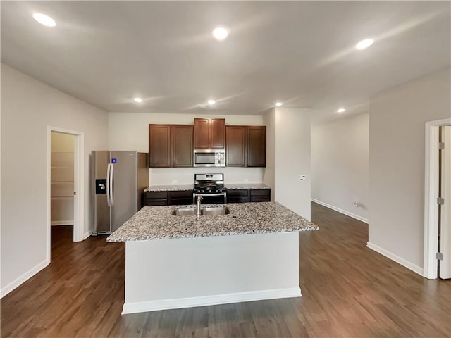 kitchen with dark wood-style floors, a center island with sink, appliances with stainless steel finishes, and a sink