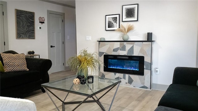 living area featuring light wood-style flooring and a glass covered fireplace