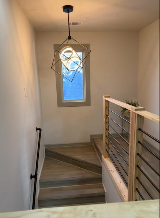 stairway with baseboards, wood finished floors, and a chandelier