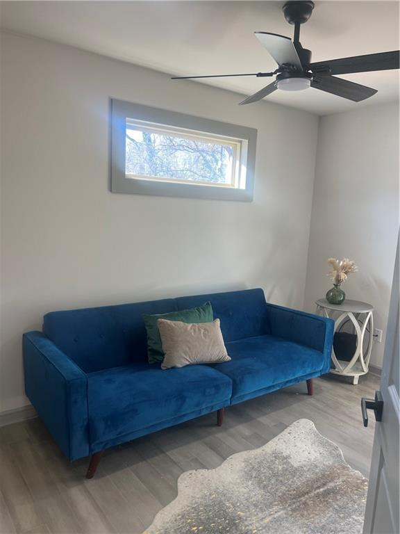 living area with wood finished floors and a ceiling fan
