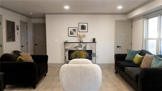 living room with baseboards, crown molding, and light wood-style floors