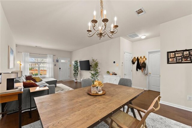 dining area featuring visible vents, baseboards, dark wood finished floors, and a chandelier