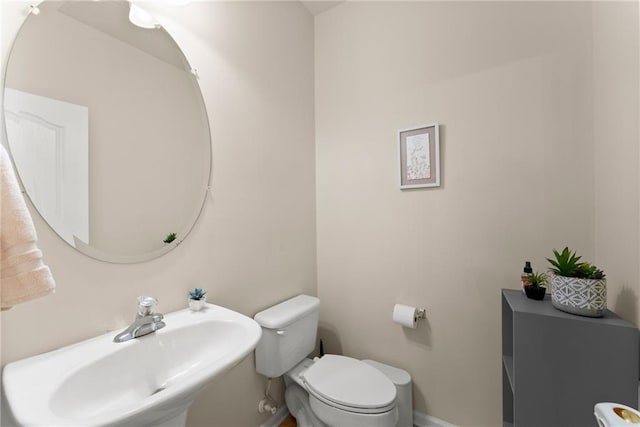 half bath with a sink, baseboards, and toilet