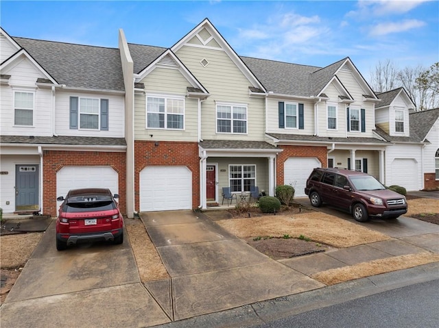 multi unit property with brick siding, an attached garage, driveway, and a shingled roof