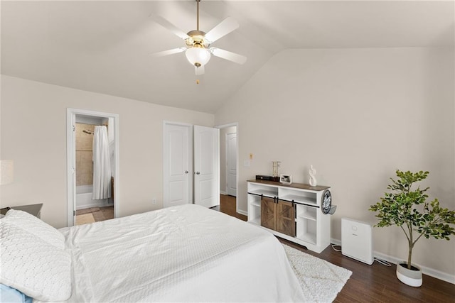 bedroom featuring baseboards, vaulted ceiling, wood finished floors, ensuite bath, and a ceiling fan