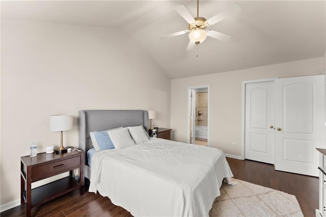 bedroom with dark wood finished floors, ensuite bath, baseboards, and vaulted ceiling