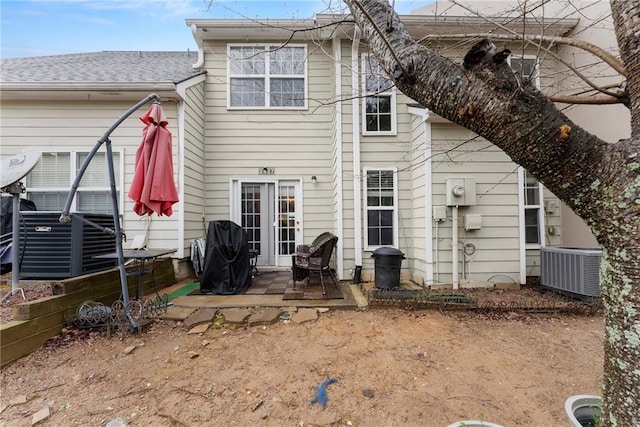 back of property with cooling unit, a patio, and roof with shingles