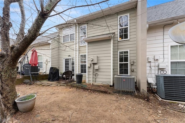 rear view of house with a patio area, central air condition unit, and roof with shingles