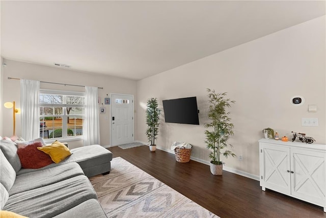 living area featuring wood finished floors, visible vents, and baseboards