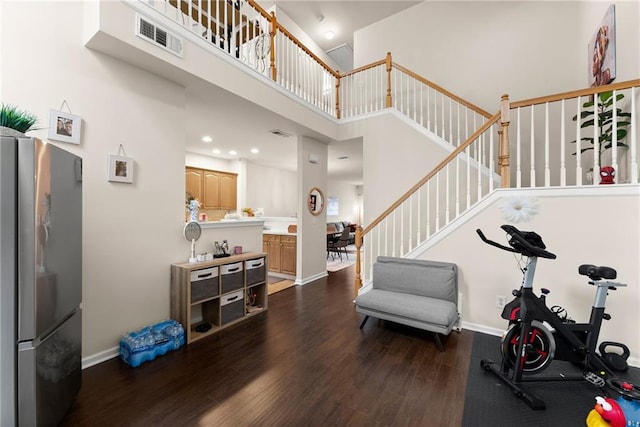 interior space featuring visible vents, baseboards, stairway, a towering ceiling, and dark wood-style flooring