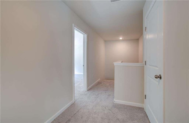 hallway featuring light colored carpet